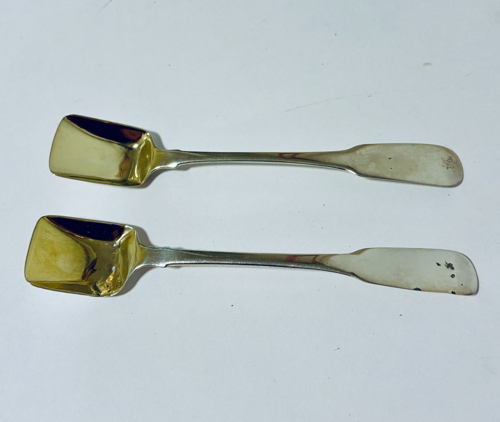 A pair of Georgian silver salt shovels featuring rectangular silver-gilt shovel bowls and smooth fiddle pattern handles.