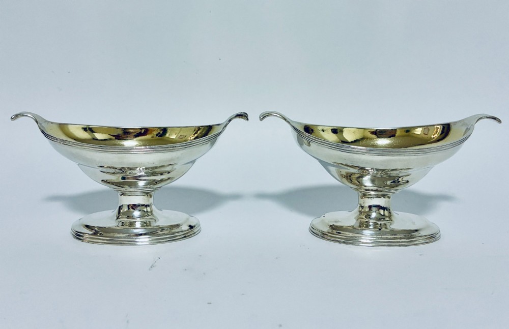 A pair of Georgian sterling silver boat-shaped salt cellars with pedestal bases and gilded interiors. View II