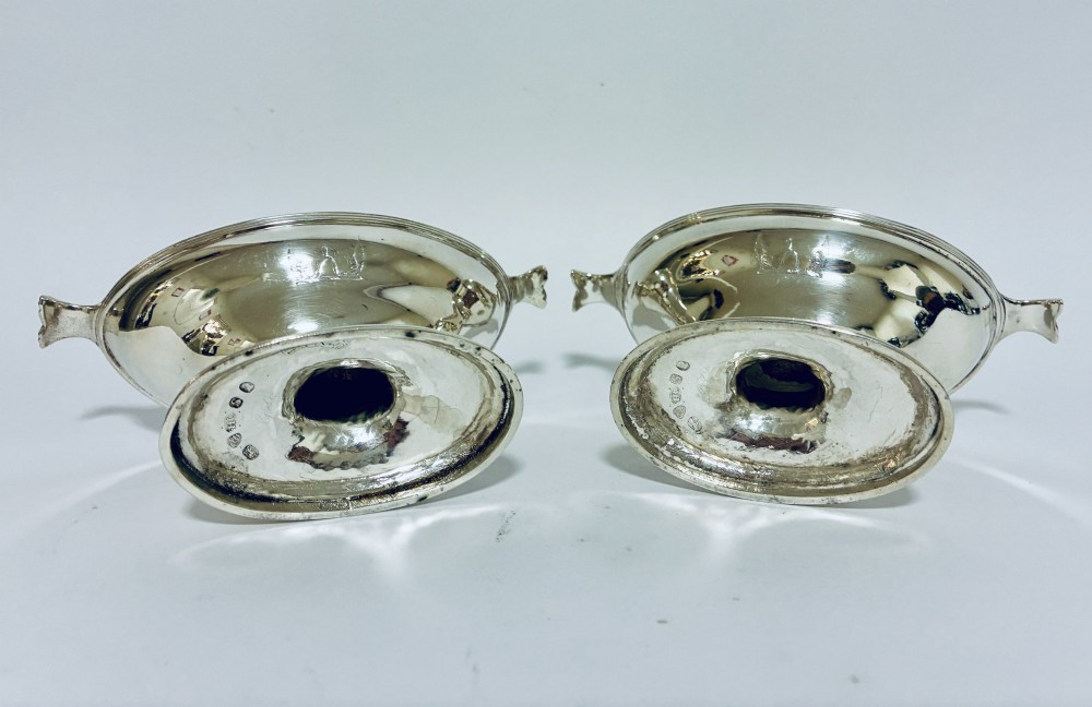 A pair of Georgian sterling silver boat-shaped salt cellars with pedestal bases and gilded interiors. View X
