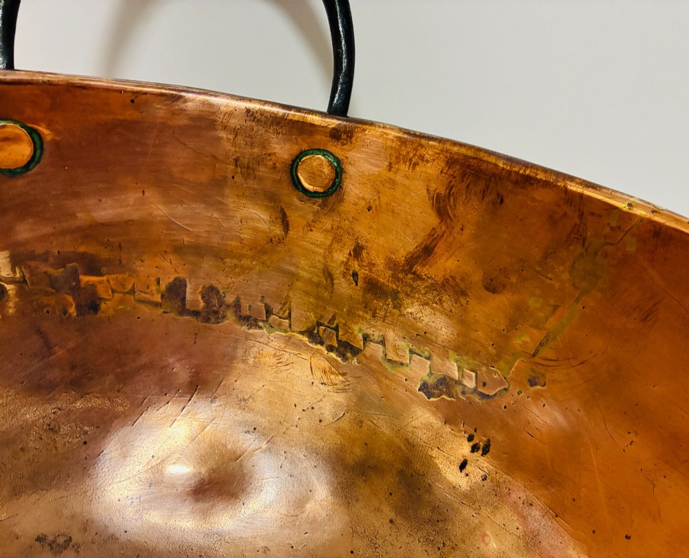 A round antique copper bowl with a wide rim and two black wrought iron handles attached with copper rivets. View IX