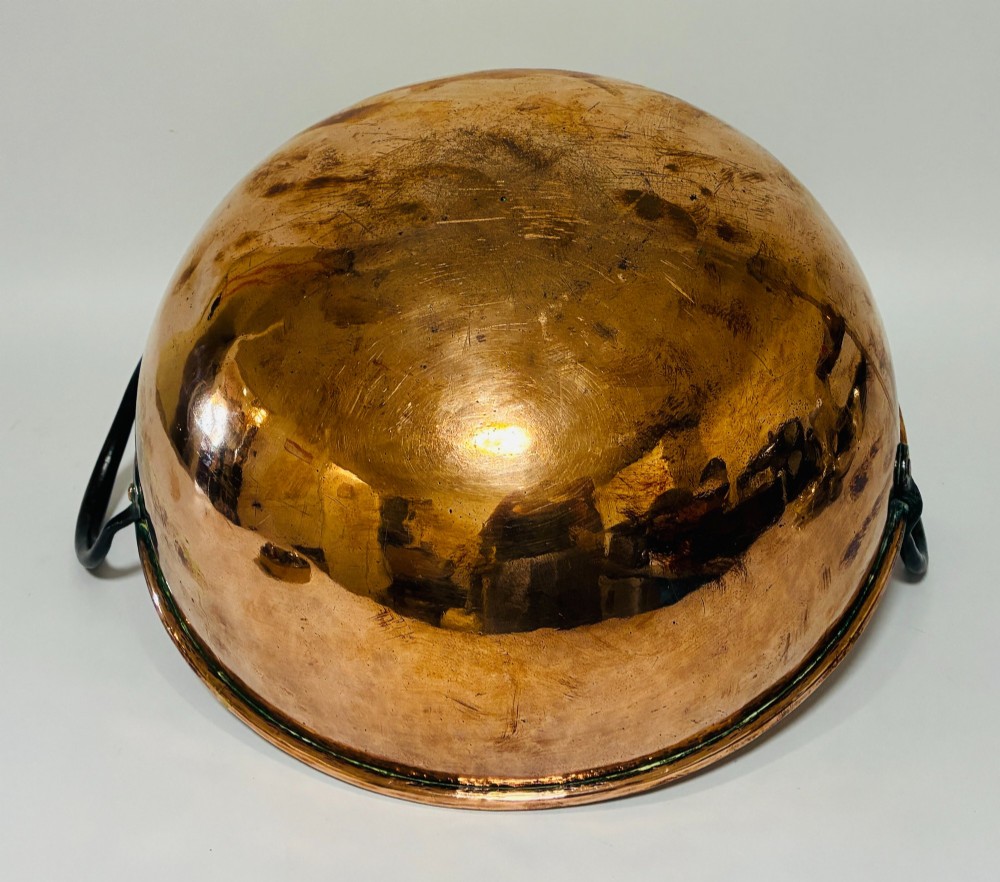 A round antique copper bowl with a wide rim and two black wrought iron handles attached with copper rivets. View XI