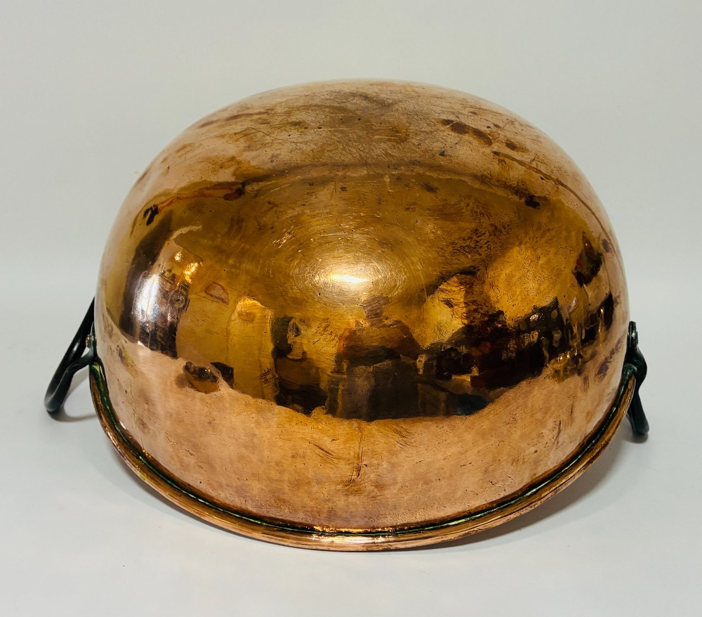 A round antique copper bowl with a wide rim and two black wrought iron handles attached with copper rivets. View XII