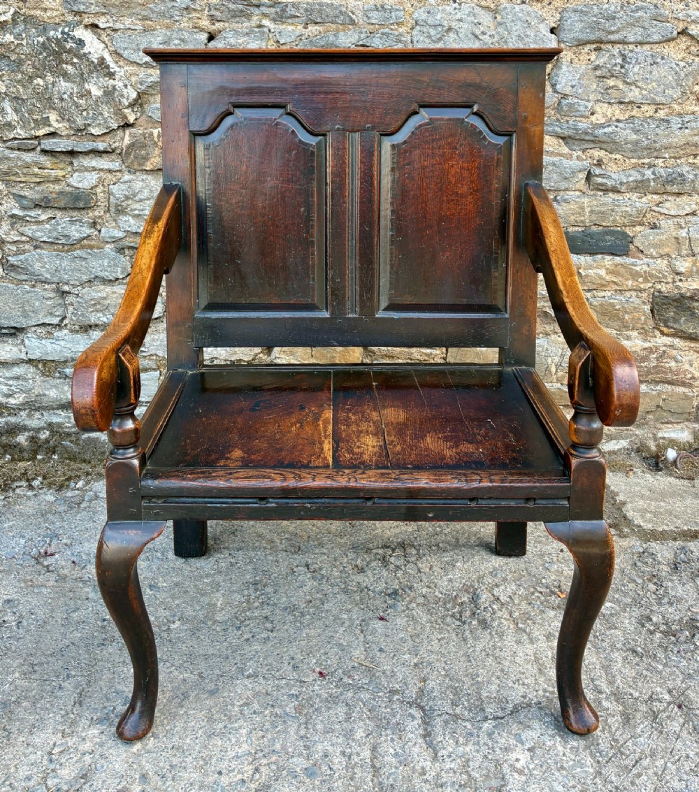 An 18th-century Georgian dark oak settle featuring a twin arched-panel back, contoured armrests, and cabriole front legs. View II