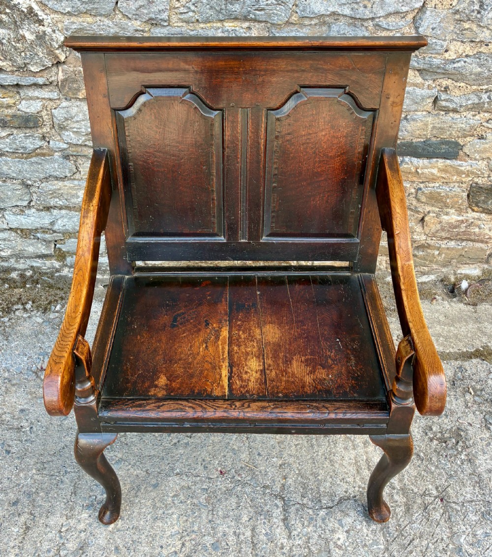 An 18th-century Georgian dark oak settle featuring a twin arched-panel back, contoured armrests, and cabriole front legs. View III