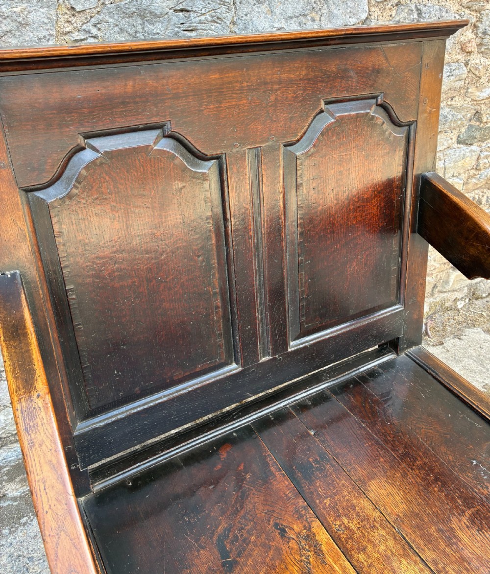 An 18th-century Georgian dark oak settle featuring a twin arched-panel back, contoured armrests, and cabriole front legs. View IX