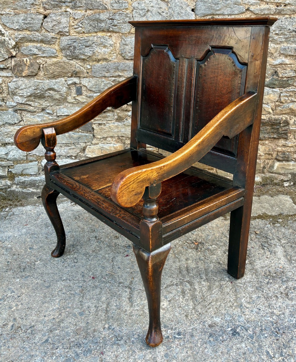 An 18th-century Georgian dark oak settle featuring a twin arched-panel back, contoured armrests, and cabriole front legs. View XI