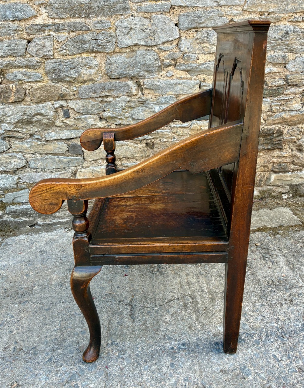 An 18th-century Georgian dark oak settle featuring a twin arched-panel back, contoured armrests, and cabriole front legs. View XII