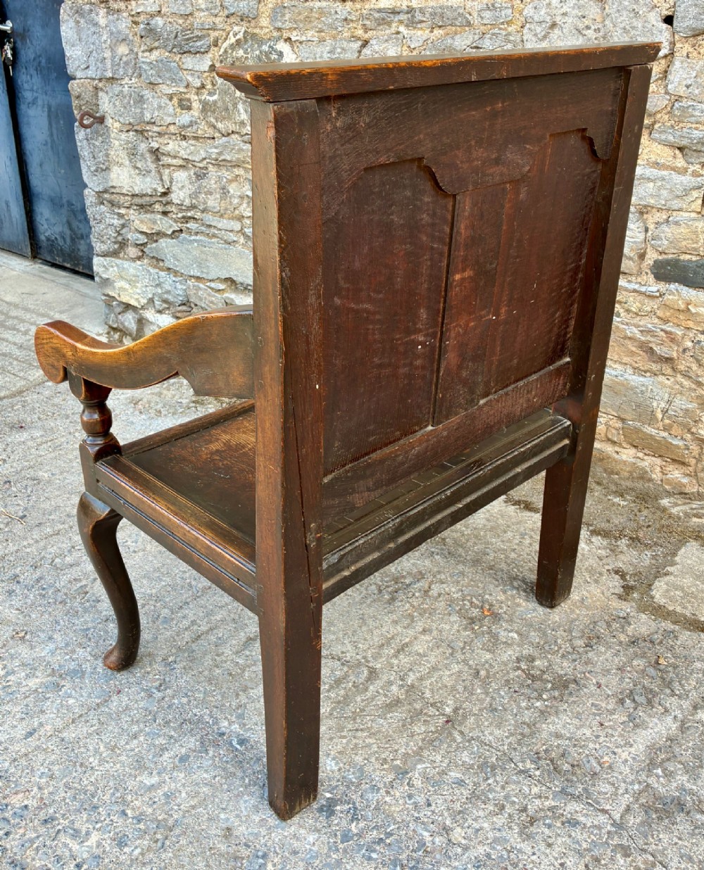 An 18th-century Georgian dark oak settle featuring a twin arched-panel back, contoured armrests, and cabriole front legs. View XIII