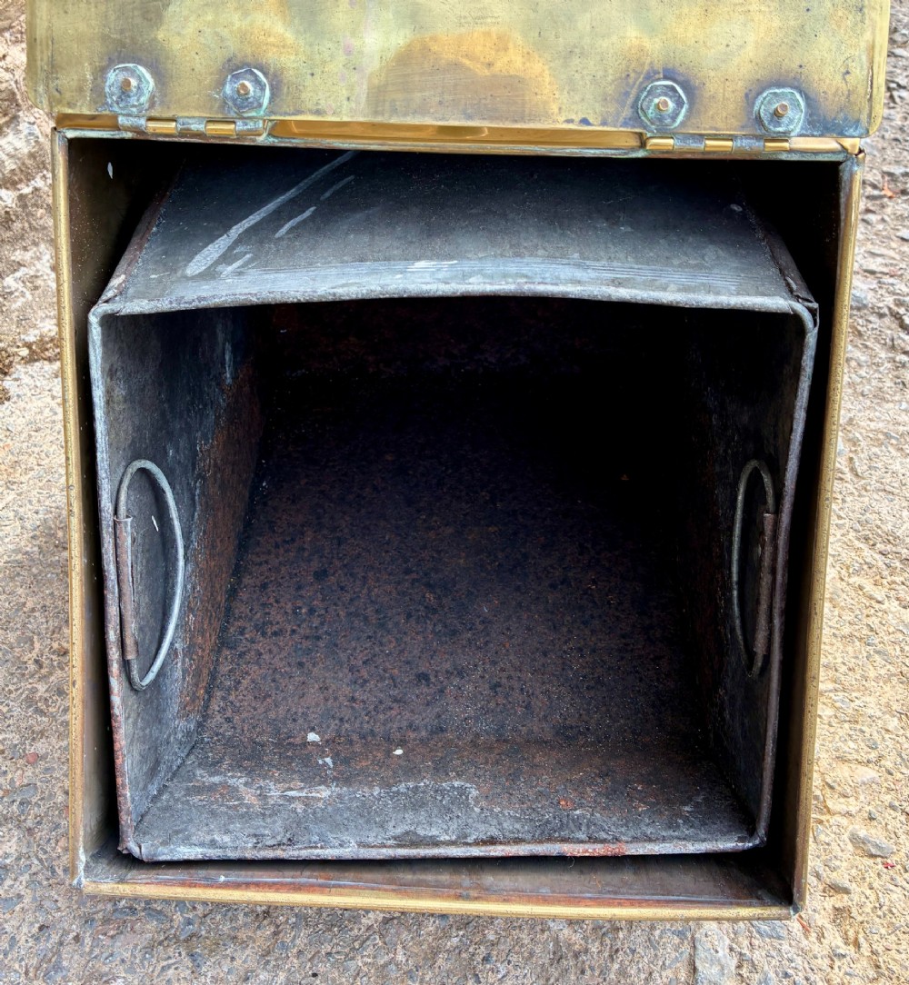 An antique brass sloped coal scuttle featuring a turned wooden carrying handle, a hinged lid, and an attached brass shovel at the rear. View XI