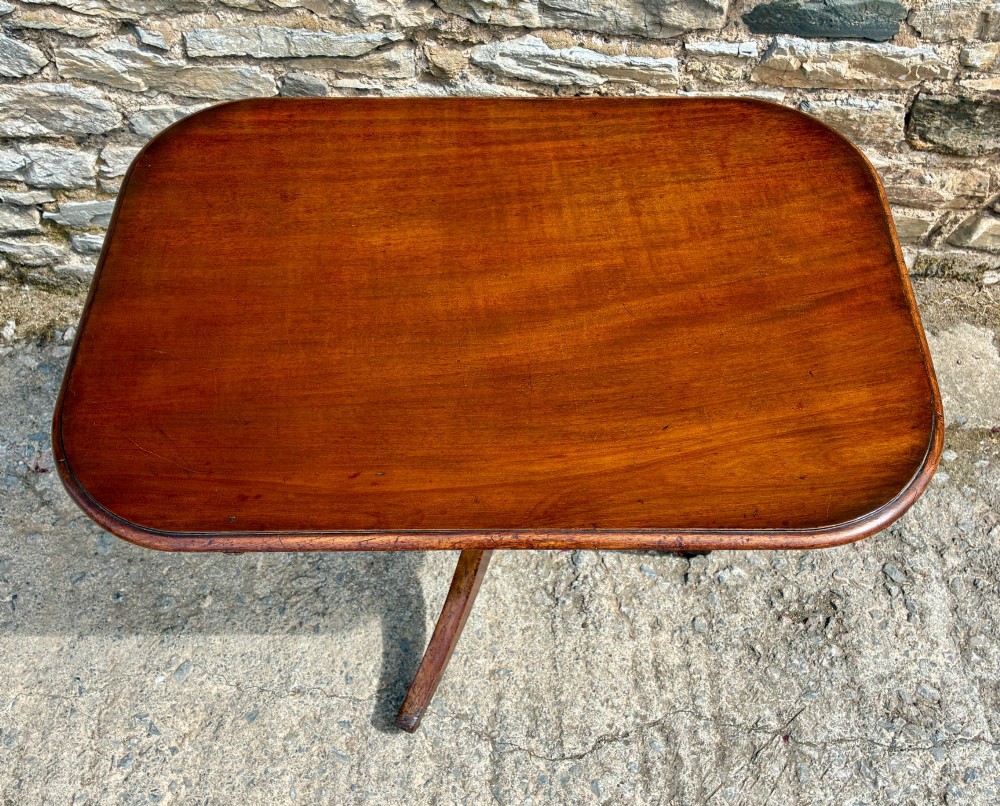 A Victorian mahogany tilt-top table featuring a polished rounded rectangular surface set on a turned pedestal column with three splayed legs. View III
