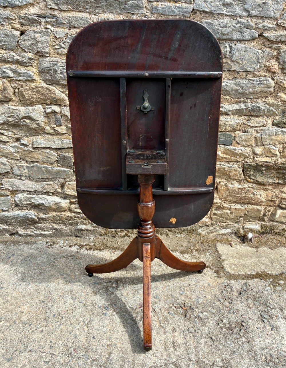 A Victorian mahogany tilt-top table featuring a polished rounded rectangular surface set on a turned pedestal column with three splayed legs. View VIII