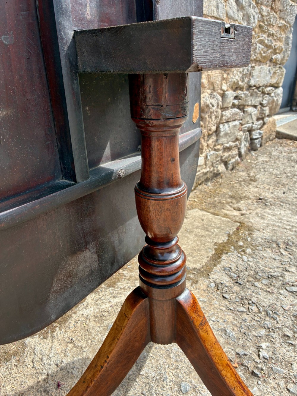 A Victorian mahogany tilt-top table featuring a polished rounded rectangular surface set on a turned pedestal column with three splayed legs. View X