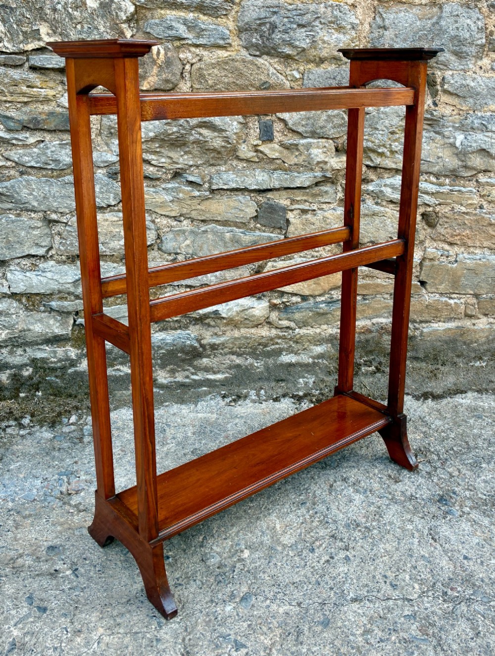 An Edwardian mahogany freestanding towel rail featuring double horizontal bars, a lower solid wooden shelf, vertical side supports, and flared feet. View IV
