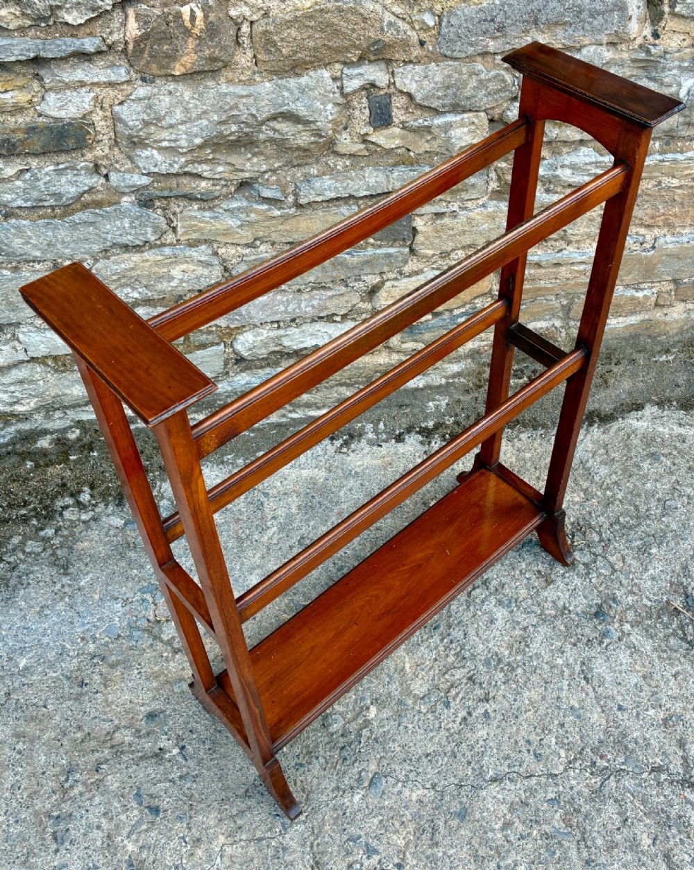 An Edwardian mahogany freestanding towel rail featuring double horizontal bars, a lower solid wooden shelf, vertical side supports, and flared feet. View V