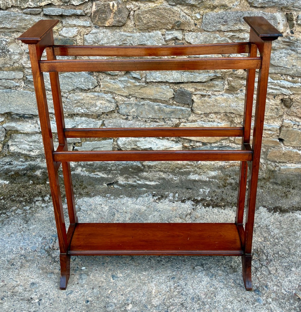 An Edwardian mahogany freestanding towel rail featuring double horizontal bars, a lower solid wooden shelf, vertical side supports, and flared feet. View VI
