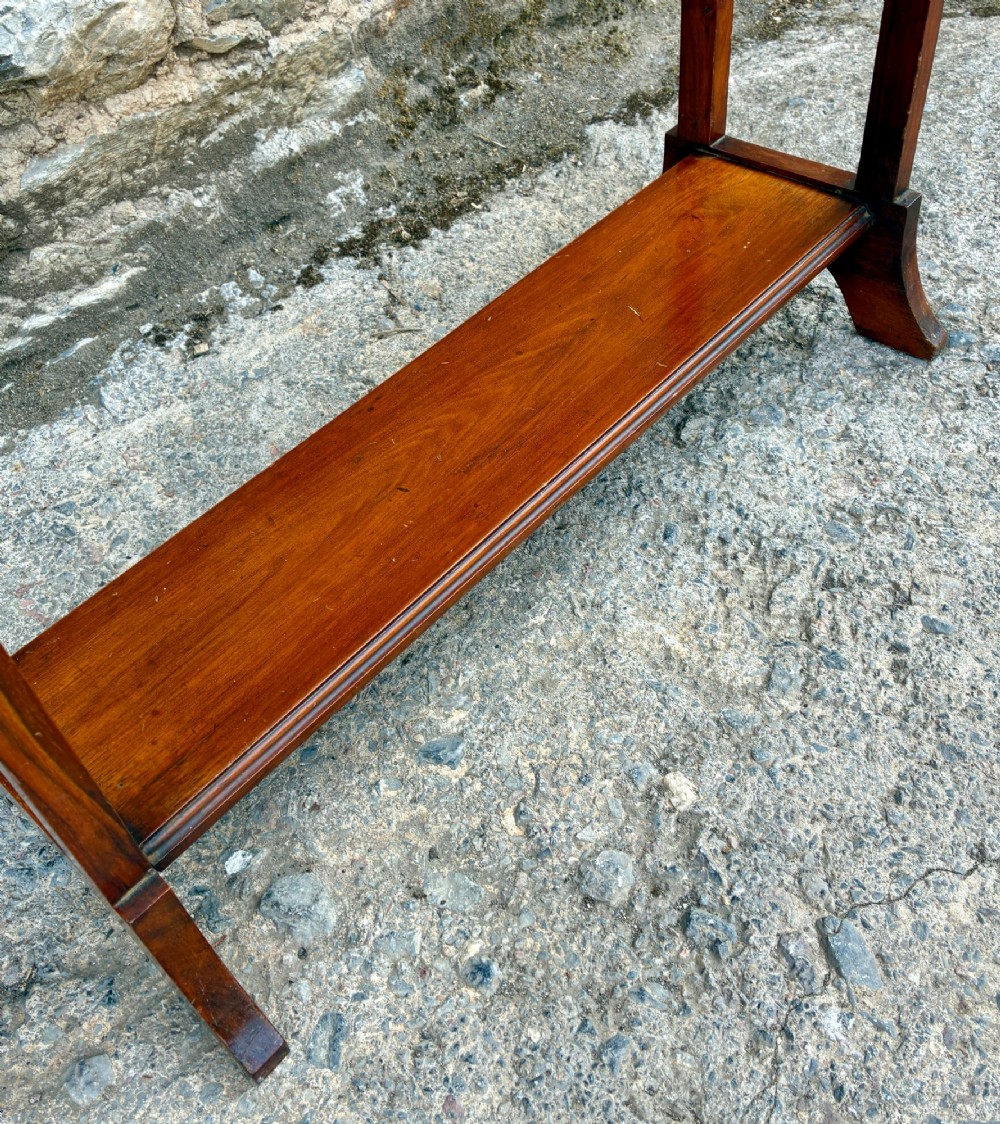 An Edwardian mahogany freestanding towel rail featuring double horizontal bars, a lower solid wooden shelf, vertical side supports, and flared feet. View VIII