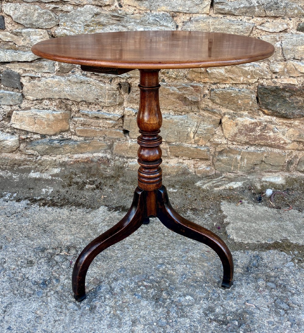 An antique Regency mahogany wine table featuring a circular top, turned pedestal stem, and three cabriole tripod legs. View II