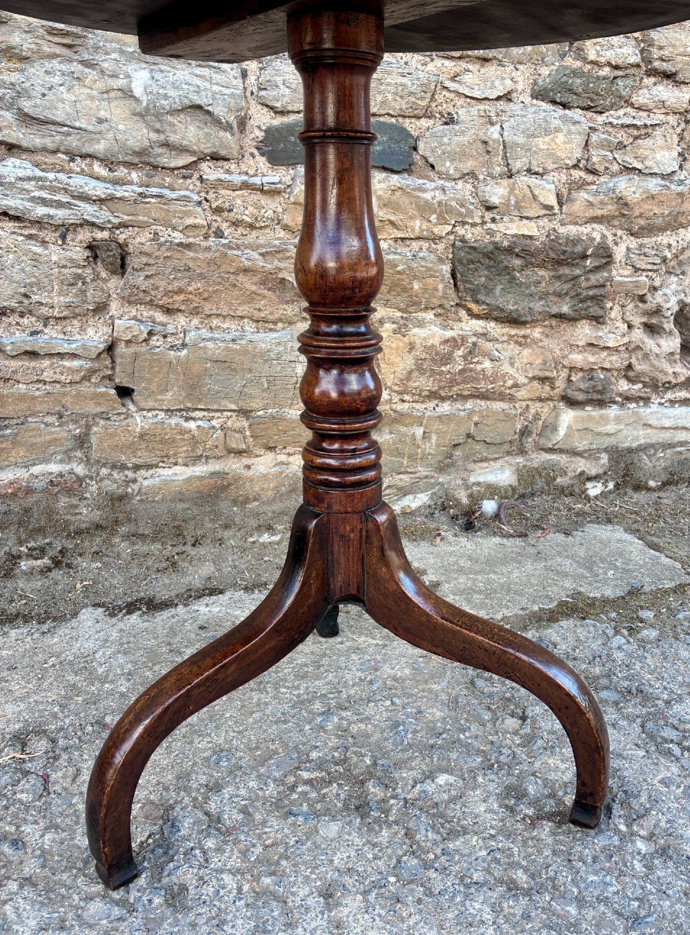 An antique Regency mahogany wine table featuring a circular top, turned pedestal stem, and three cabriole tripod legs. View VII