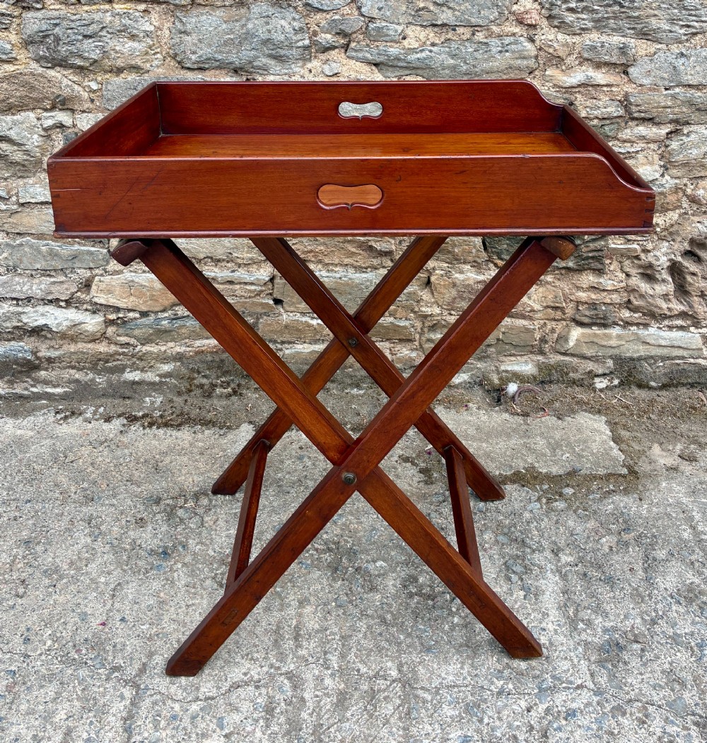 A Victorian mahogany butlers tray with cut-out hand holes resting on a folding wooden X-frame stand. View VI