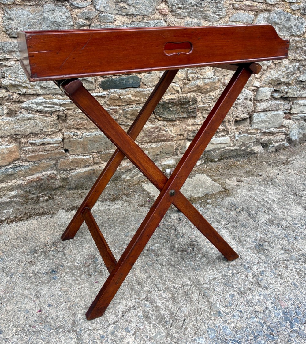 A Victorian mahogany butlers tray with cut-out hand holes resting on a folding wooden X-frame stand. View VII