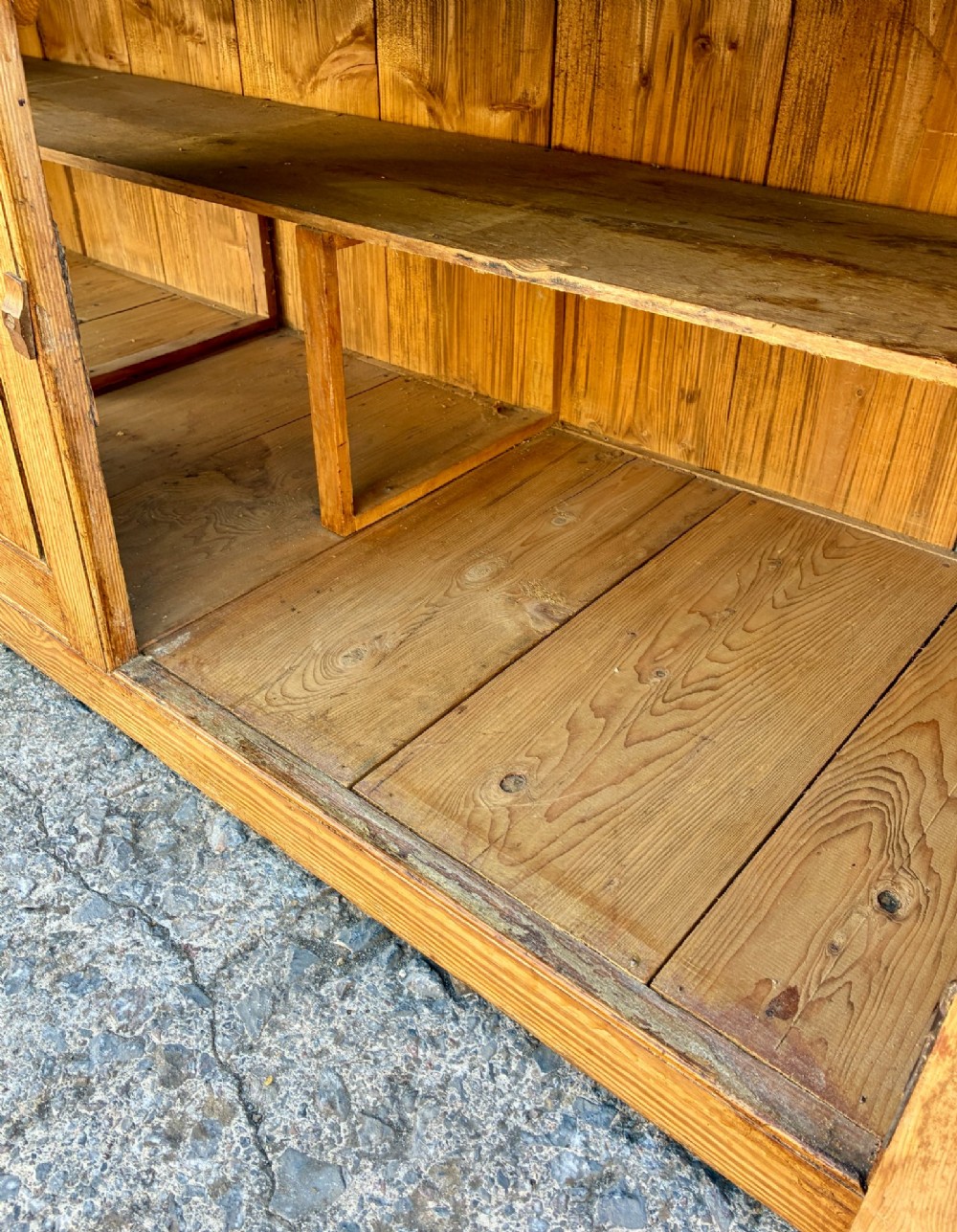 A nineteenth-century pine dresser base featuring three top drawers, three lower panelled cupboard doors, and turned dark wooden knobs. View XIII