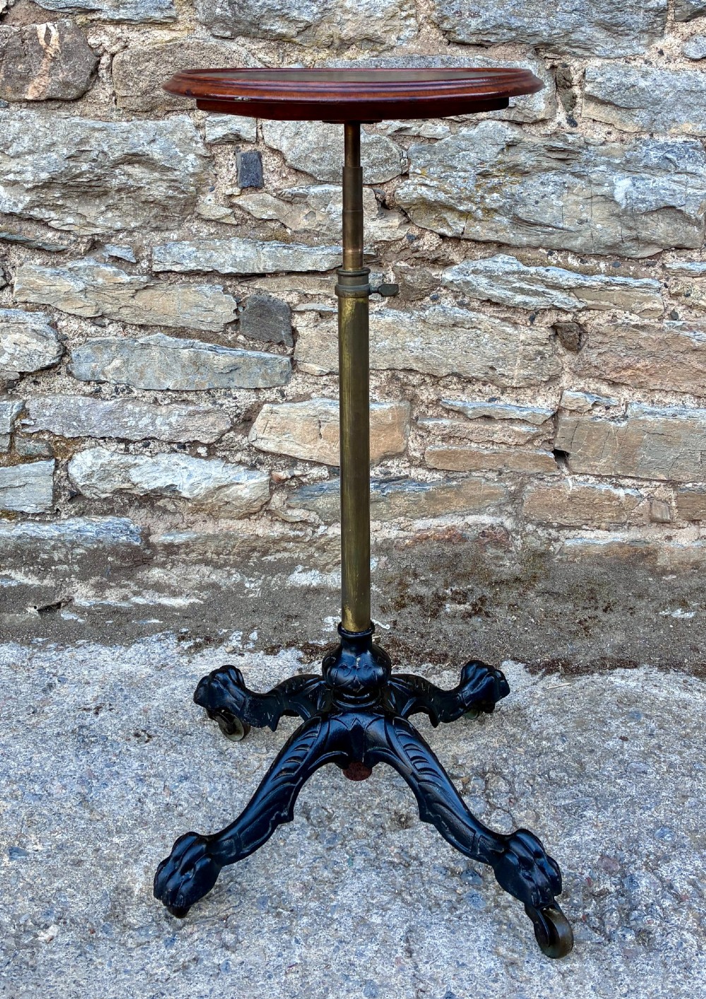 Victorian adjustable display stand featuring a round mahogany top, a brass telescoping stem, and a black cast iron paw-foot base. View II