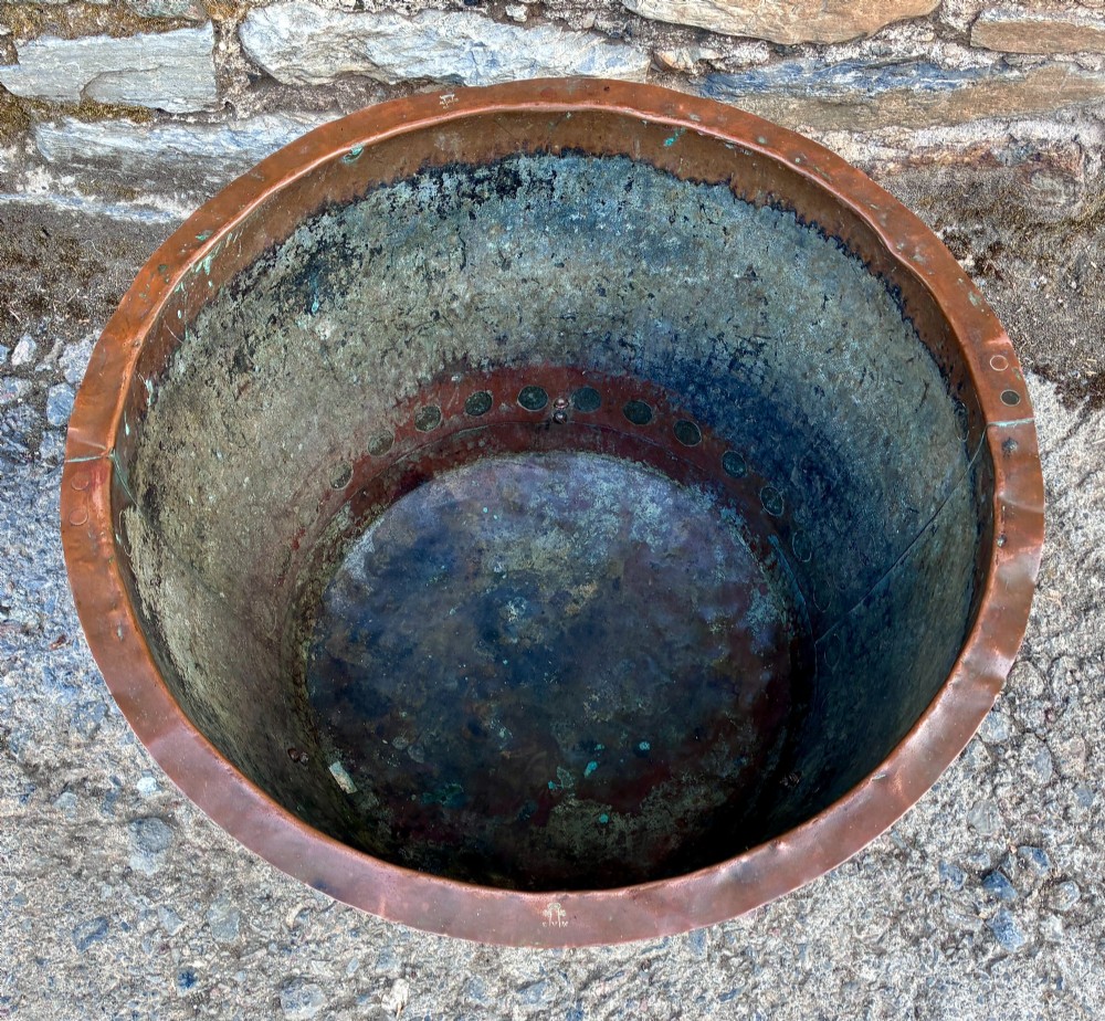 A large round copper boiler with a hand-riveted base seam and flared rim, supported on four decorative cast brass claw feet. View II