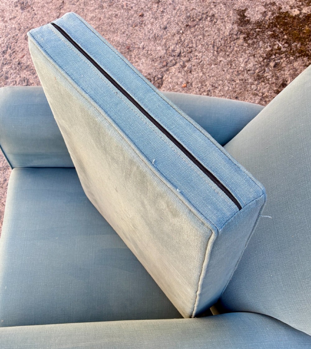 An Edwardian deep-seated armchair upholstered in light blue woven fabric with scrolled arms and dark wood legs on brass castors. View X