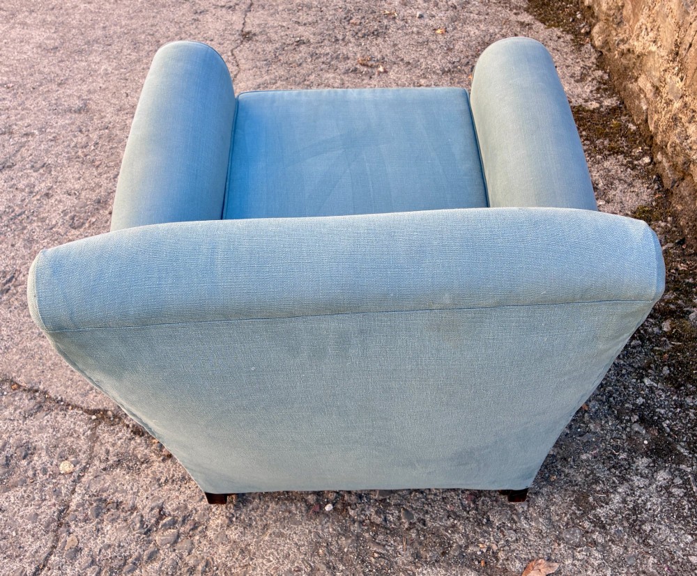 An Edwardian deep-seated armchair upholstered in light blue woven fabric with scrolled arms and dark wood legs on brass castors. View XIII