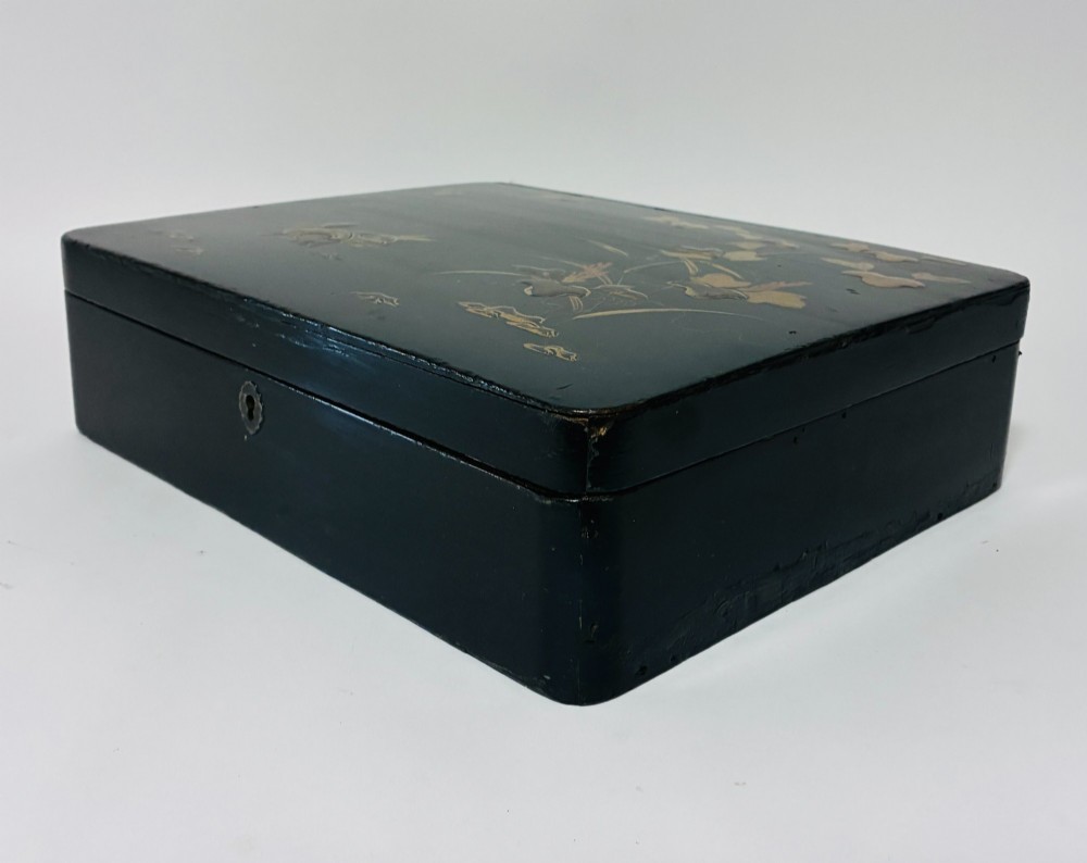 A rectangular black lacquered box decorated with gold maki-e depictions of rabbits and foliage, featuring a central metal keyhole. View V