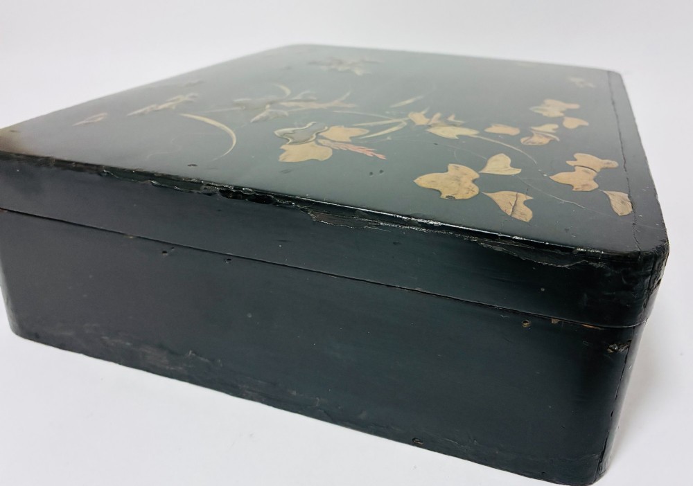 A rectangular black lacquered box decorated with gold maki-e depictions of rabbits and foliage, featuring a central metal keyhole. View VII