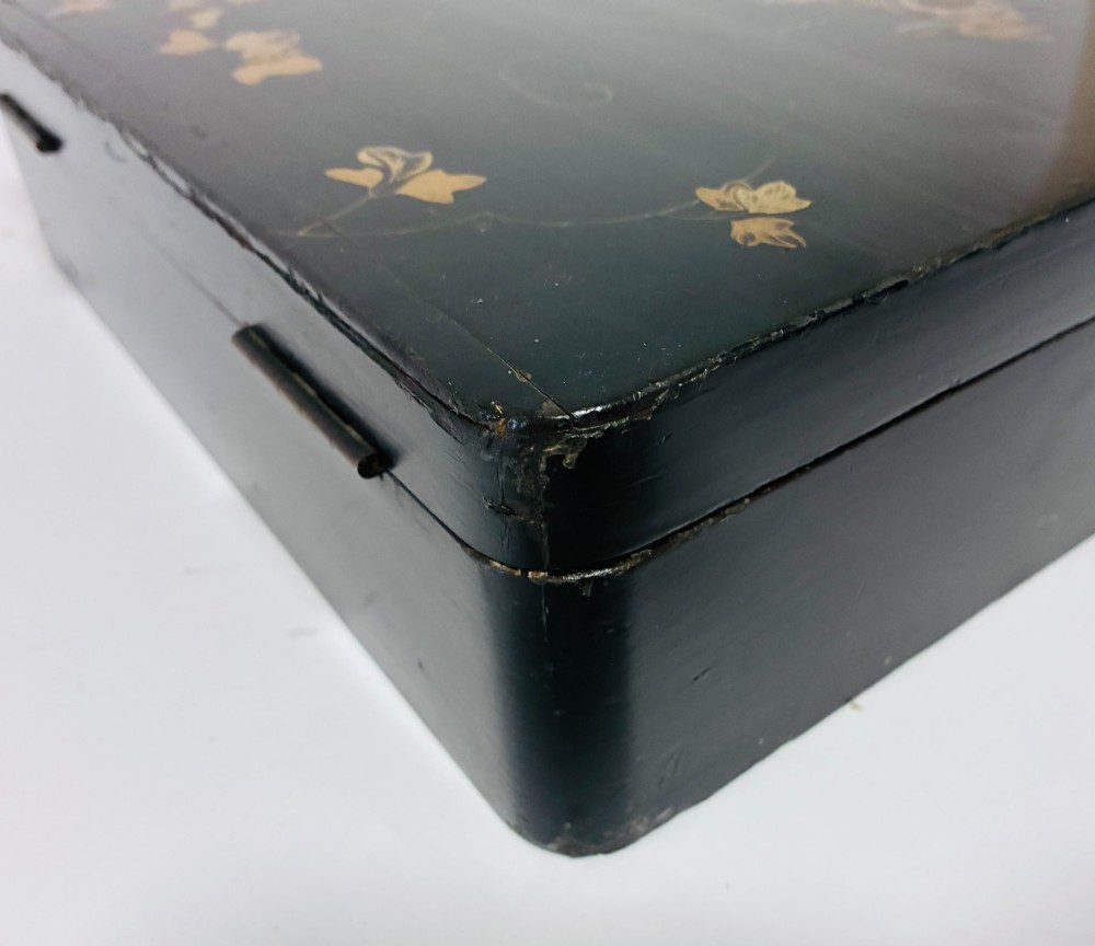 A rectangular black lacquered box decorated with gold maki-e depictions of rabbits and foliage, featuring a central metal keyhole. View X