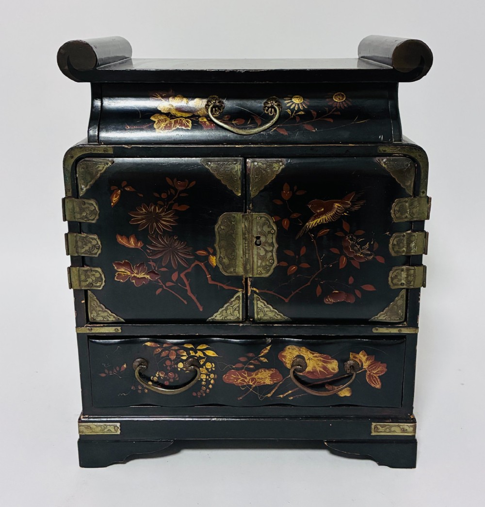 A black lacquered Japanese tabletop cabinet featuring hand-painted botanical motifs and decorative engraved brass corner mounts. View II