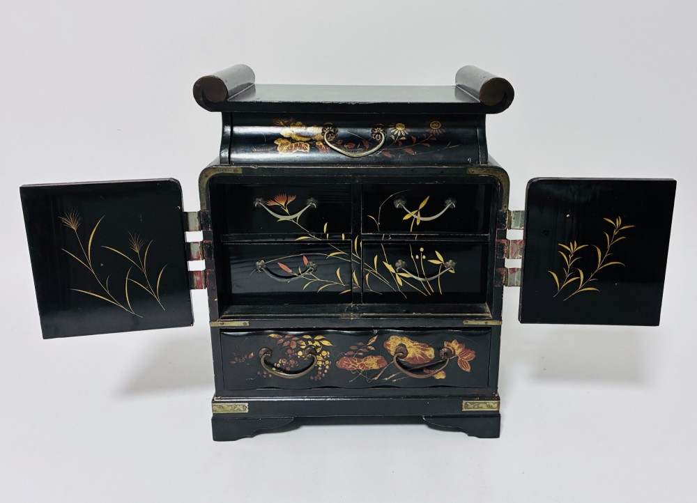 A black lacquered Japanese tabletop cabinet featuring hand-painted botanical motifs and decorative engraved brass corner mounts. View V