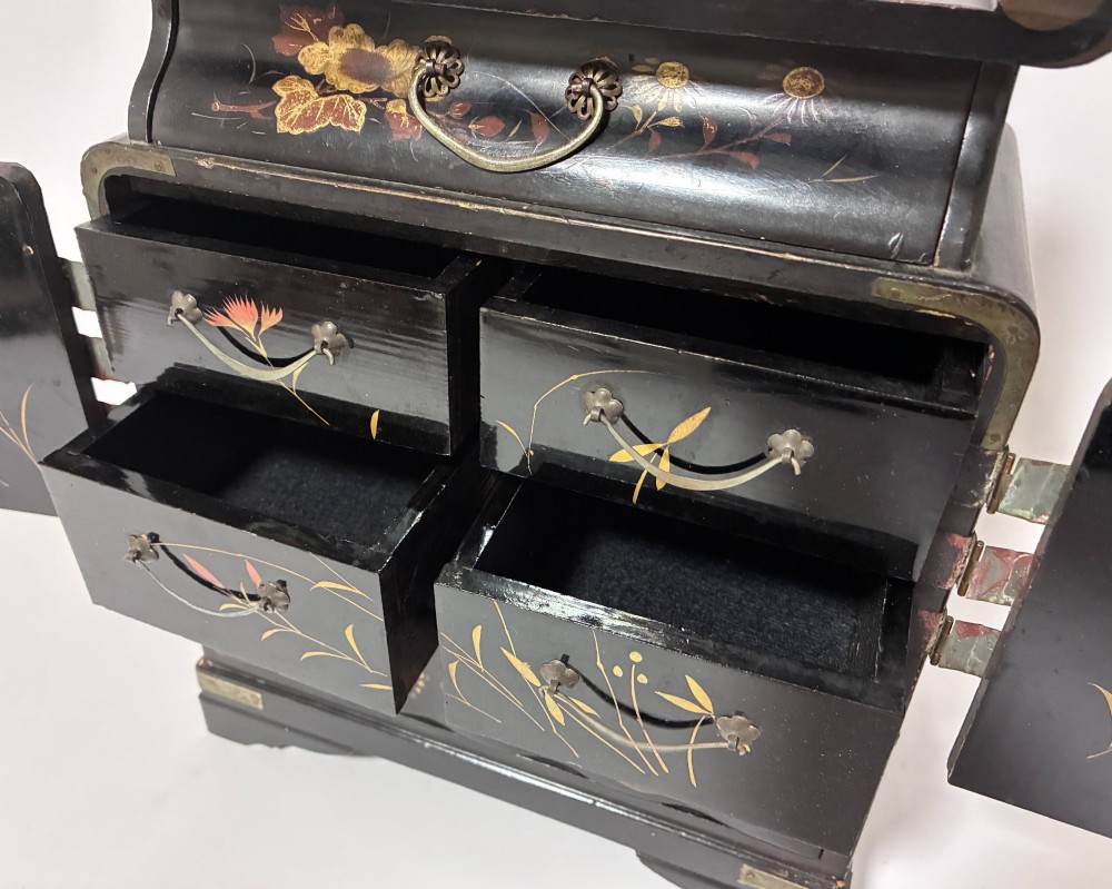 A black lacquered Japanese tabletop cabinet featuring hand-painted botanical motifs and decorative engraved brass corner mounts. View VI