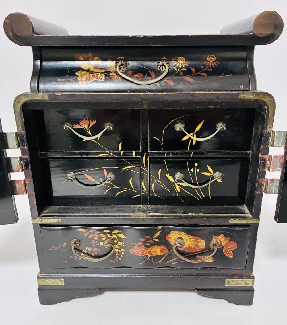 A black lacquered Japanese tabletop cabinet featuring hand-painted botanical motifs and decorative engraved brass corner mounts. View VII