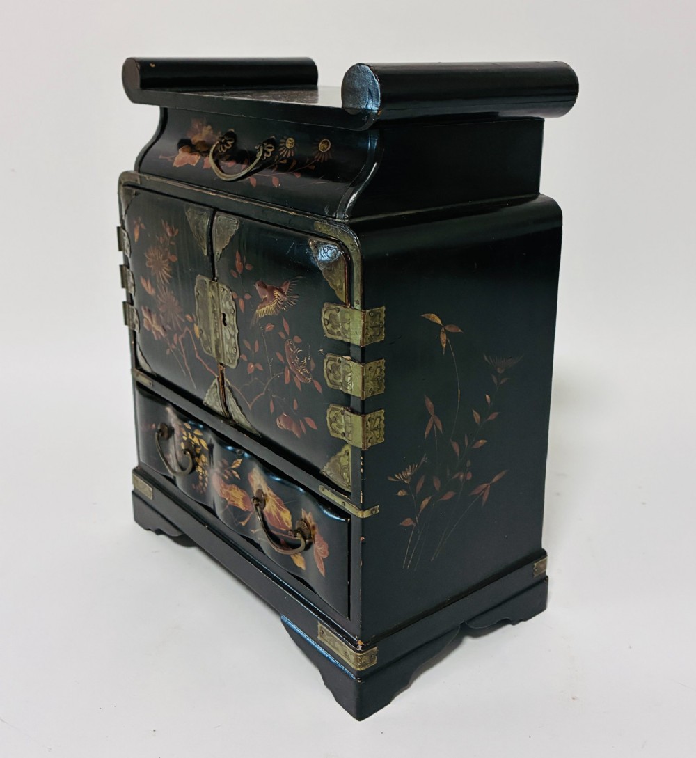 A black lacquered Japanese tabletop cabinet featuring hand-painted botanical motifs and decorative engraved brass corner mounts. View IX