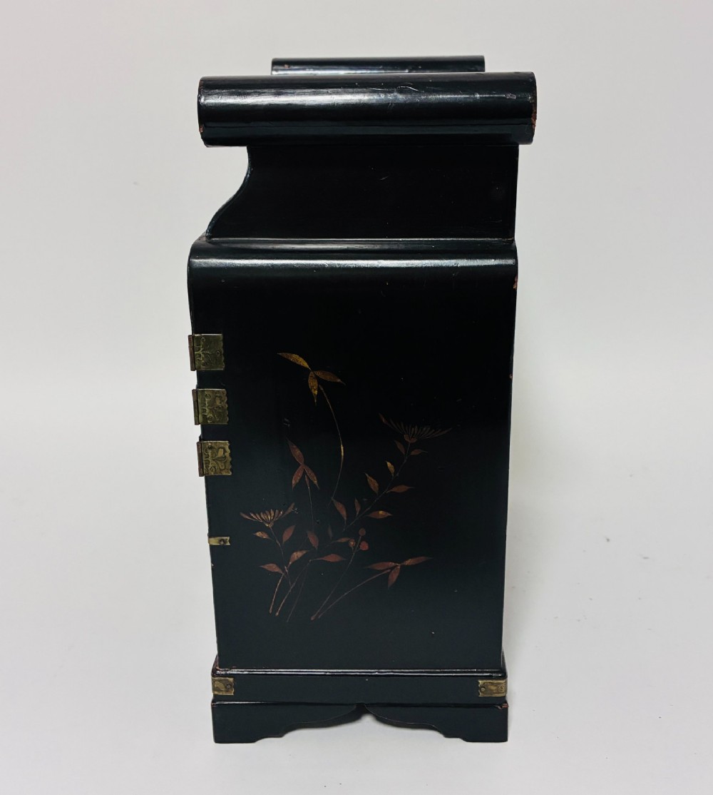 A black lacquered Japanese tabletop cabinet featuring hand-painted botanical motifs and decorative engraved brass corner mounts. View X