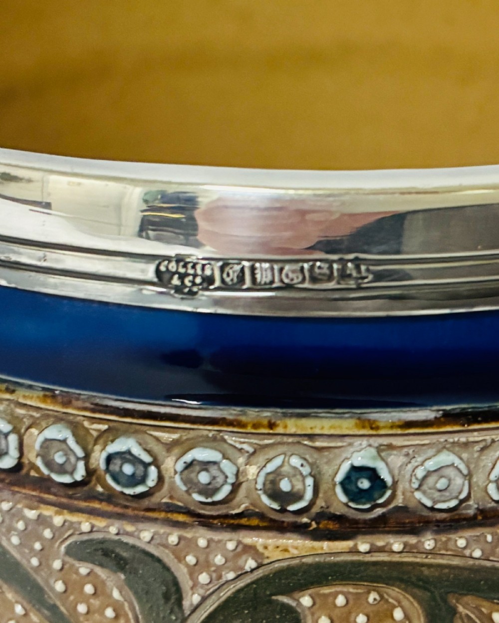 A cylindrical Victorian Doulton Lambeth stoneware biscuit barrel featuring cobalt blue and beige scrollwork decoration, fitted with a silver-plated lid, swing handle, and finial. View IX