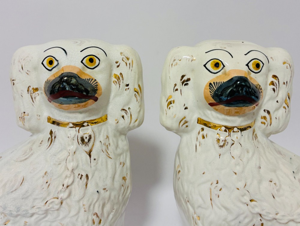 A pair of white glazed earthenware Staffordshire dog figures with hand-painted gold details and expressive facial features. View II