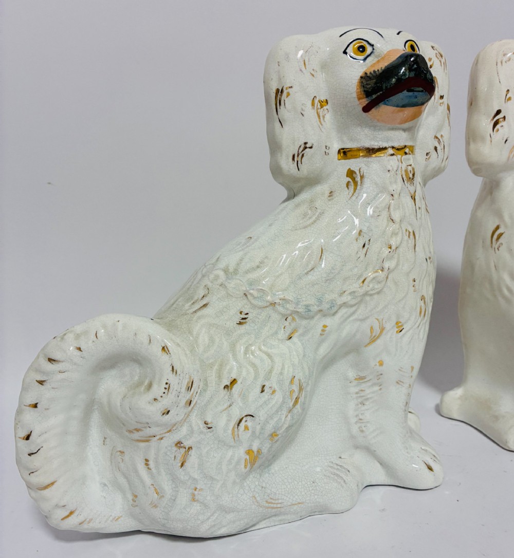 A pair of white glazed earthenware Staffordshire dog figures with hand-painted gold details and expressive facial features. View III