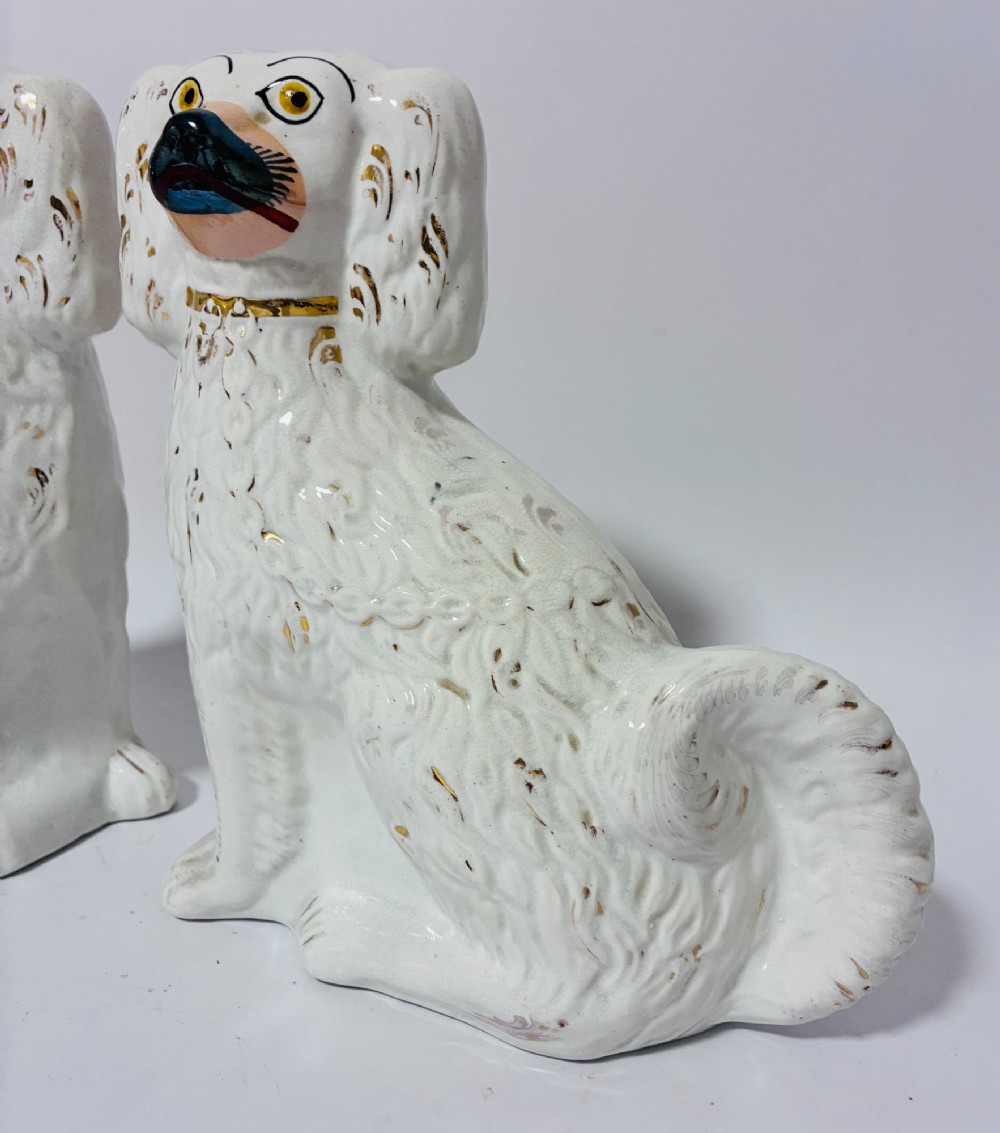 A pair of white glazed earthenware Staffordshire dog figures with hand-painted gold details and expressive facial features. View IV