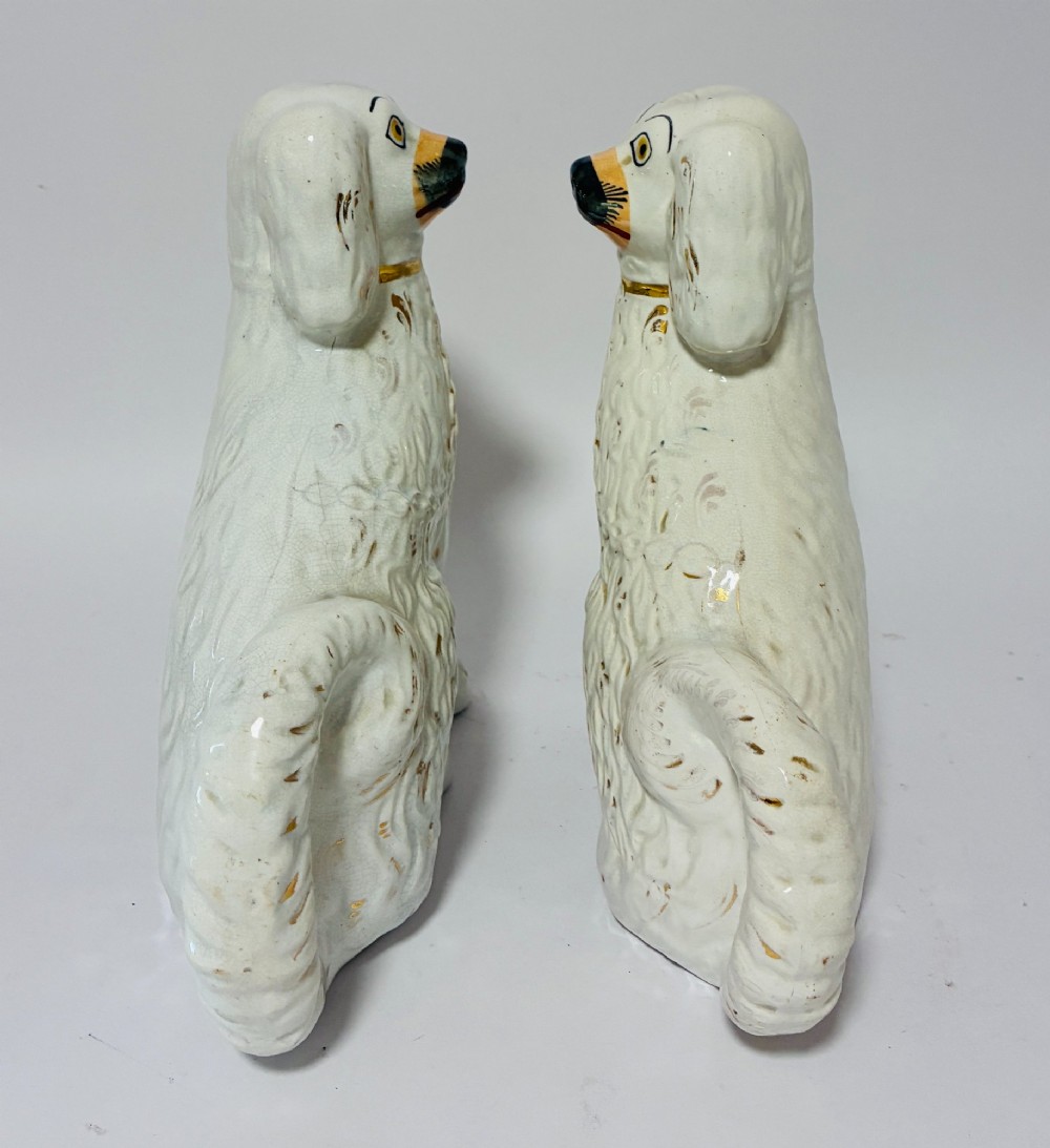 A pair of white glazed earthenware Staffordshire dog figures with hand-painted gold details and expressive facial features. View IX