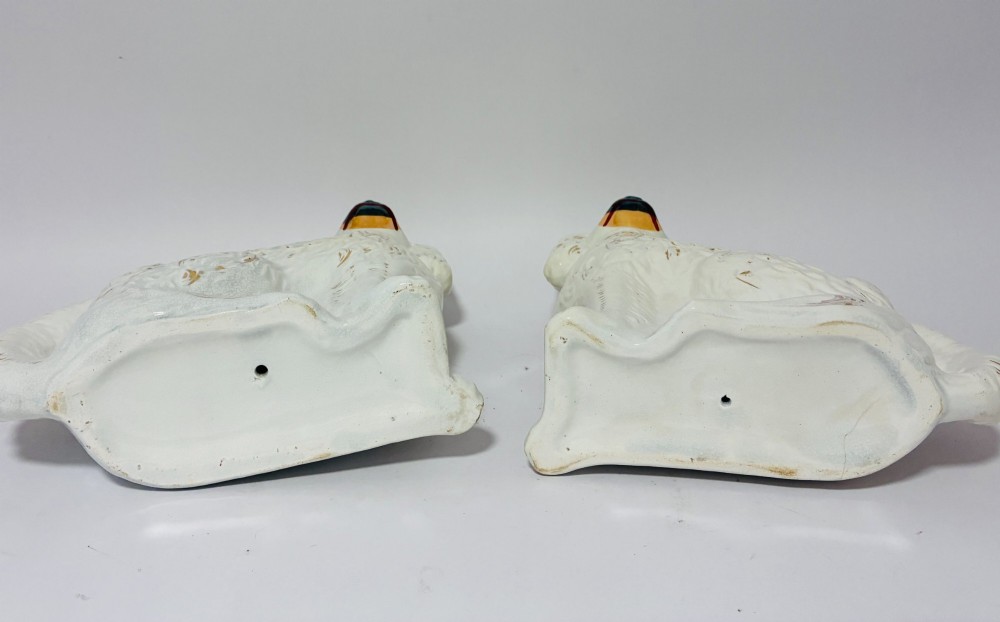 A pair of white glazed earthenware Staffordshire dog figures with hand-painted gold details and expressive facial features. View X