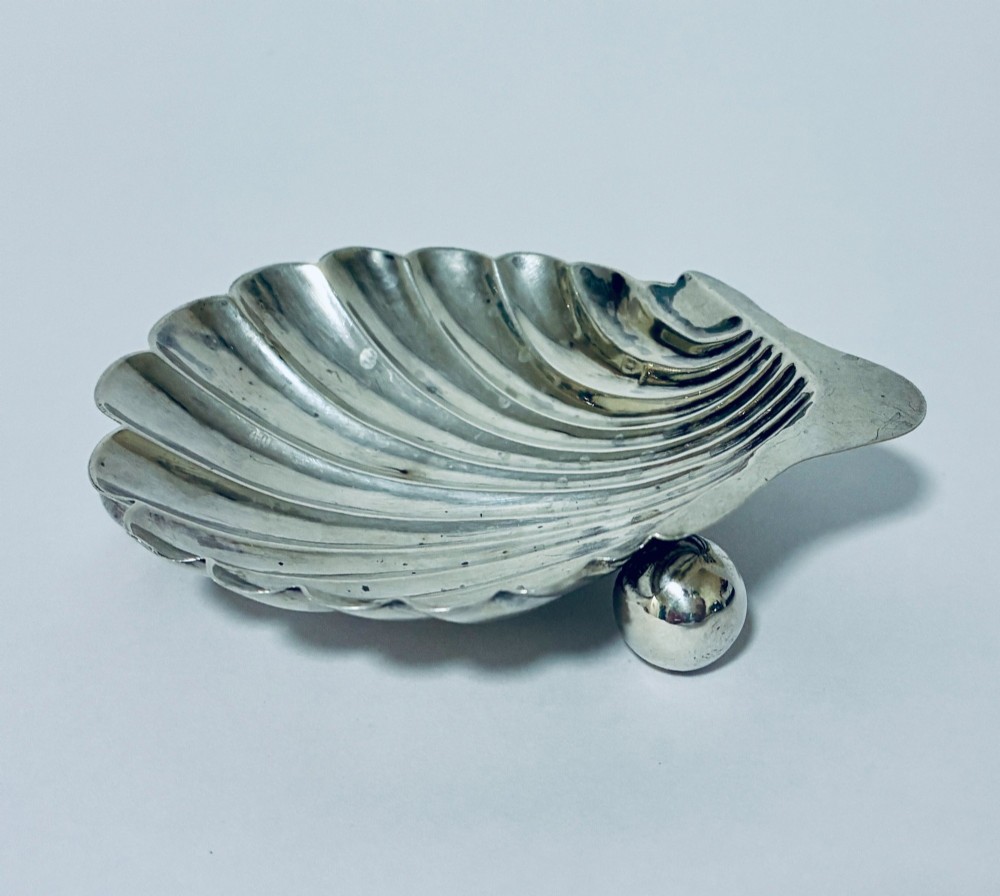 An antique silver-plated butter dish designed in the shape of a scalloped shell with fluted ridges and small ball feet. View III