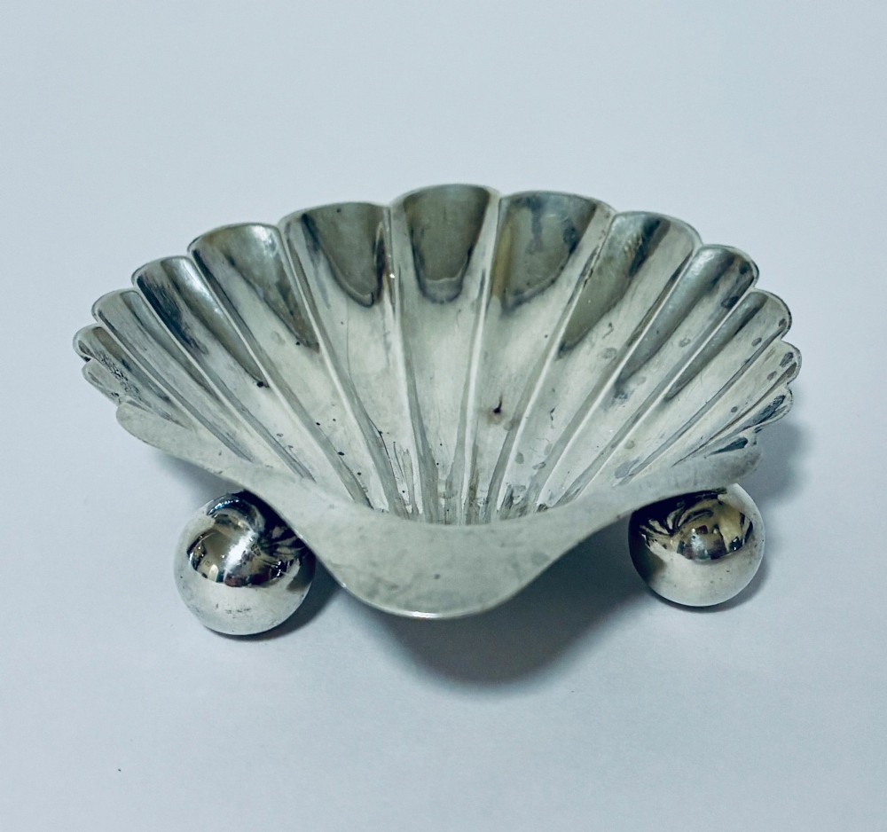 An antique silver-plated butter dish designed in the shape of a scalloped shell with fluted ridges and small ball feet. View IV