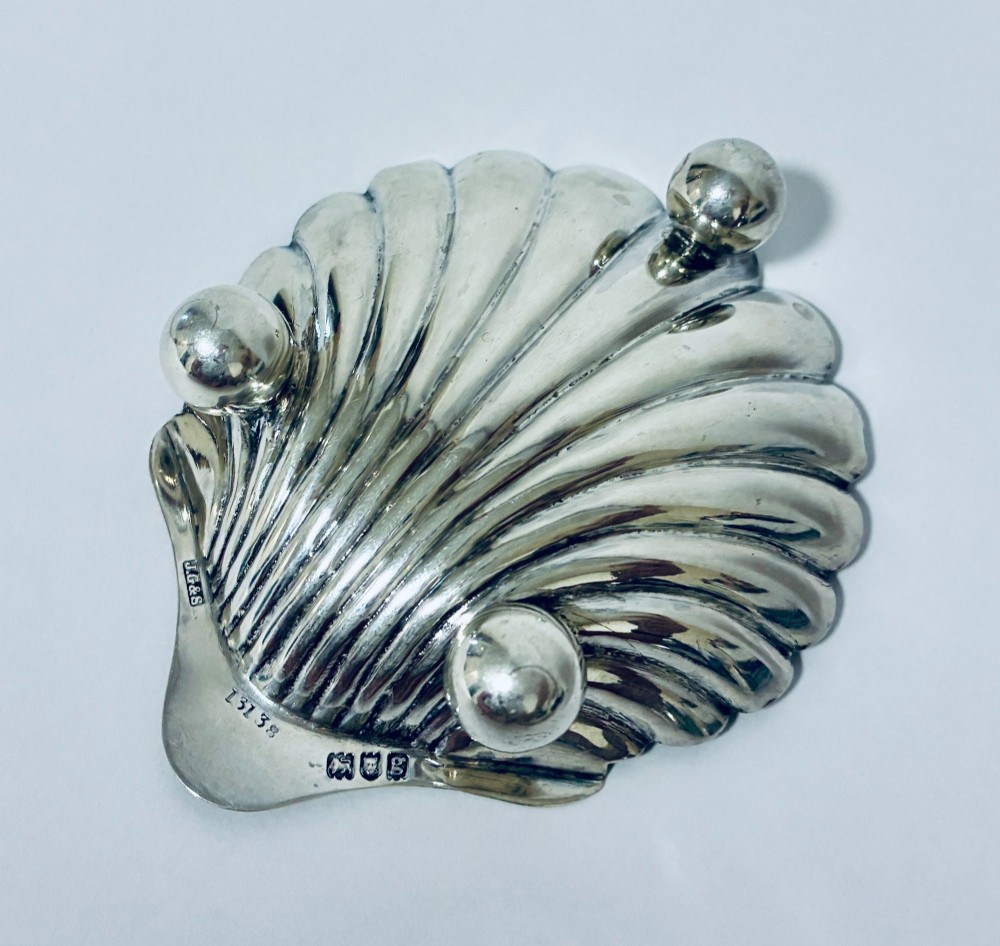 An antique silver-plated butter dish designed in the shape of a scalloped shell with fluted ridges and small ball feet. View VII