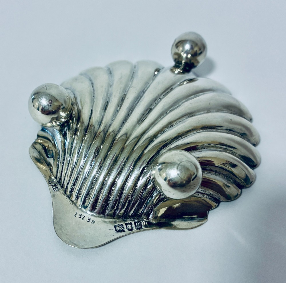 An antique silver-plated butter dish designed in the shape of a scalloped shell with fluted ridges and small ball feet. View VIII