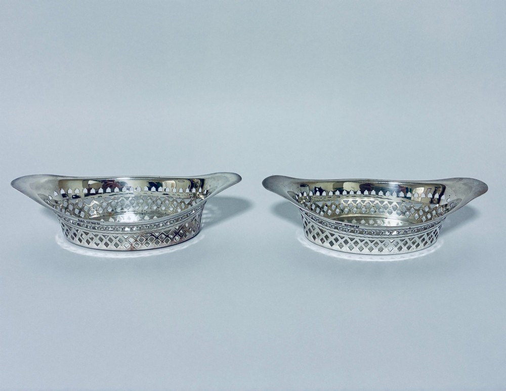 A pair of oval Victorian silver bonbon dishes featuring lattice-pierced reticulated sides and flared handles.
