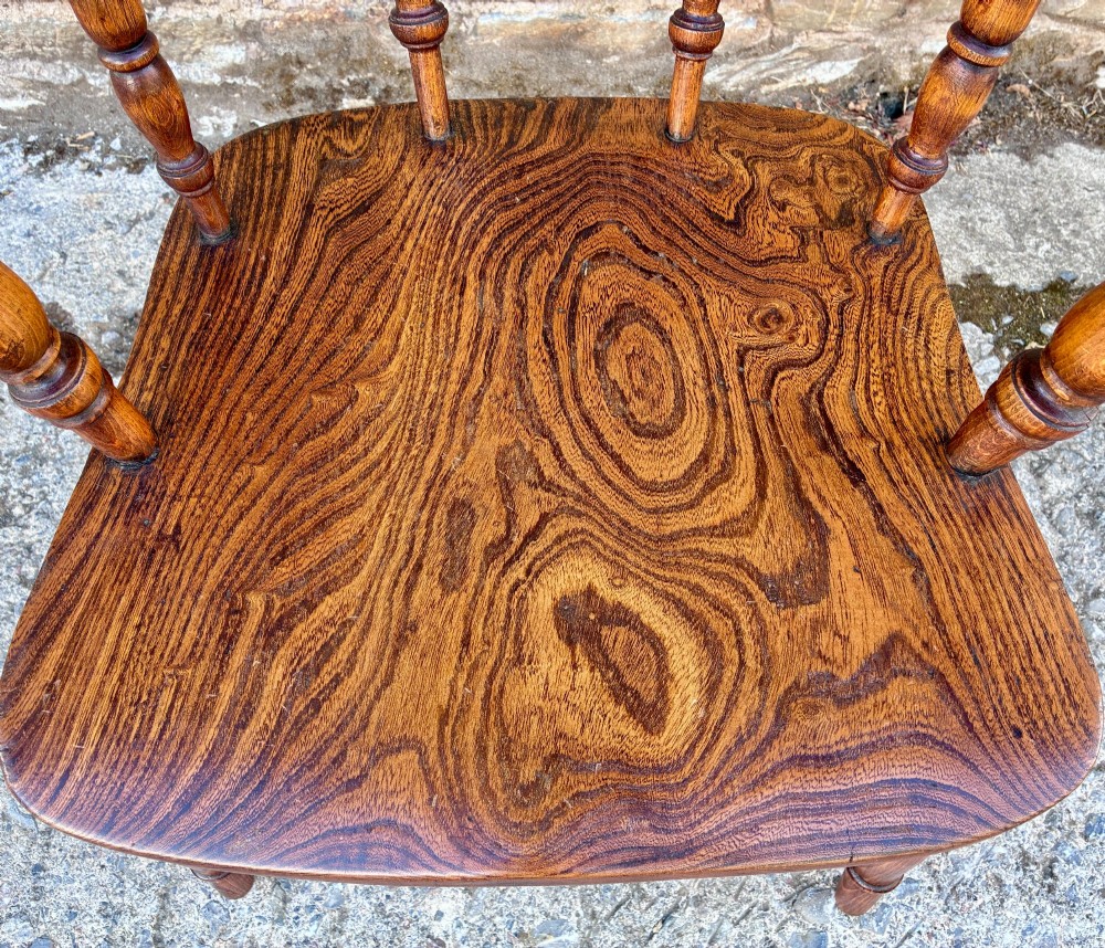 A Victorian elm captains armchair featuring a curved horseshoe rail, turned wooden spindles, and a deeply contoured saddle seat showing prominent wood grain. View IV